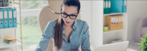 woman sitting at desk with glasses looking a paperwork